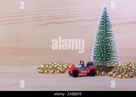 Rouge-argent jouet voiture mini, mini-arbre de Noël avec de la neige et des petites boules d'or sur le fond de bois. Banque D'Images