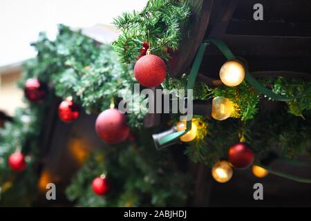 Arbre de Noël avec de la neige artificielle décorée de pommes de pin et red tree ornament baubles et la chaîne de lumières en arrière-plan Banque D'Images