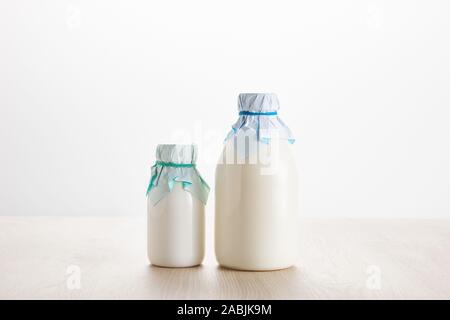 Divers produits laitiers biologiques frais dans des bouteilles sur la table en bois isolé sur blanc Banque D'Images