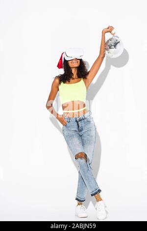 Cheerful african american woman holding disco ball et debout avec la main dans la poche on white Banque D'Images