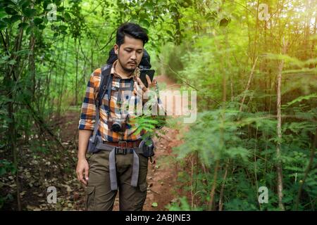 Sac à dos homme voyageur avec l'utilisation de smartphone dans la forêt naturelle Banque D'Images
