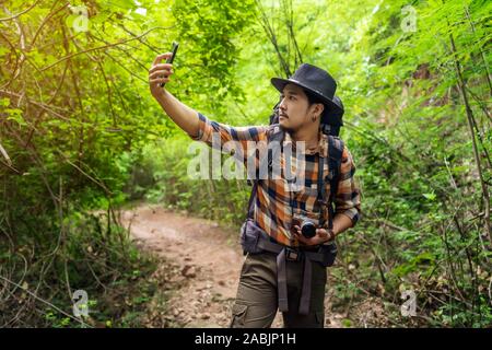 Sac à dos homme voyageur avec la recherche de signal de réception du téléphone mobile dans la forêt naturelle. Banque D'Images