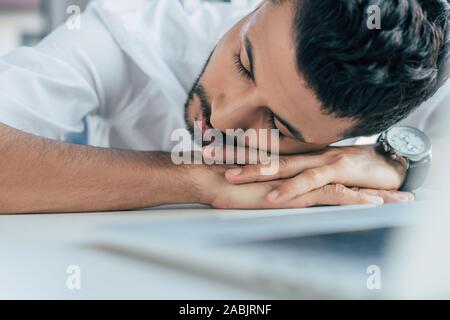 Beau, épuisé businessman sleeping tout en restant assis sur le lieu de travail Banque D'Images