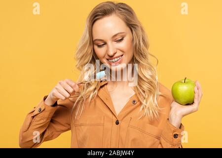 Femme souriante avec appareil dentaire holding toothbrush et vert jaune isolé sur apple Banque D'Images