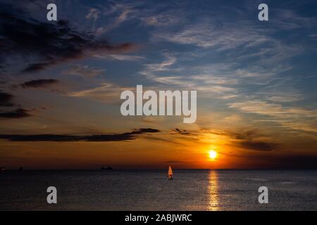 Lonely Wind surfer de mettre les voiles vers le spectaculaire et panoramique magnifique coucher de soleil à la côte de la mer méditerranée à Trieste, Italie Banque D'Images