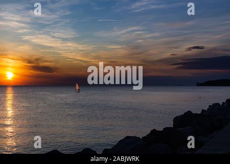 Lonely Wind surfer de mettre les voiles vers le spectaculaire et panoramique magnifique coucher de soleil à la côte de la mer méditerranée à Trieste, Italie Banque D'Images