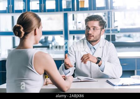 Focus sélectif de beau médecin dans les verres à la recherche au patient et gesticulant en clinique Banque D'Images