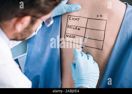 Focus sélectif de l'allergologue holding pipette près de patient avec les lettres sur le corps marqués Banque D'Images