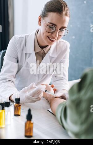 Heureux allergologue holding syringe près de l'homme en clinique Banque D'Images