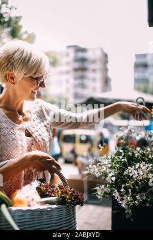 Attractive senior woman shopping dans un marché en plein air les fleurs fraîches Banque D'Images