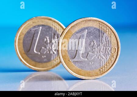 Deux pièces d'un euro rayé bleu sur un fond réfléchissant avec reflets dans les coins Banque D'Images