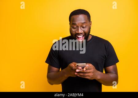 Photo de race mixte dentelée bel homme aux cheveux drôles brunet en t-shirt heureux de recevoir des commentaires positifs de notification des isolés Banque D'Images