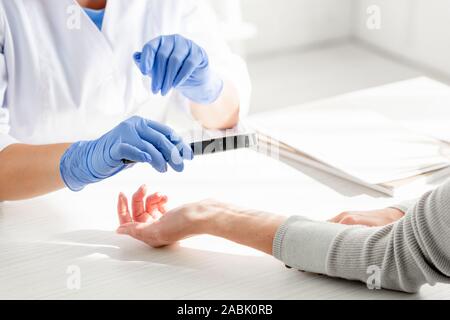 Portrait de dermatologist examining patient de la peau avec une loupe en clinique Banque D'Images