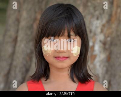 Jeune fille birman avec des correctifs de thanaka cosmétique traditionnelle face sur ses joues pose pour la caméra. Banque D'Images