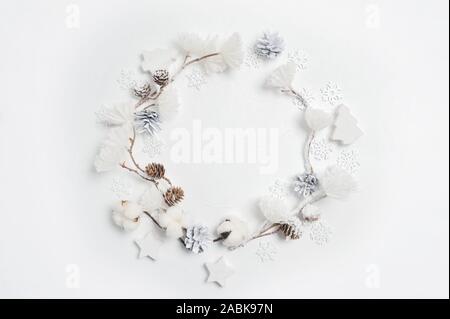 Couronne de Noël faits de flocons de coton, fleurs, pommes de pin et blanc fleur pompons. Arrière-plan blanc. Mise à plat, vue du dessus Banque D'Images