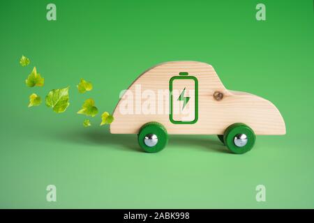 Concept de voiture écologique. Voiture jouet en bois avec des feuilles et des symboles 110impressionné sur le côté. Banque D'Images