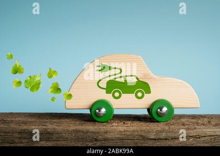 Concept de voiture écologique. Voiture jouet en bois avec des feuilles et des symboles 110impressionné sur le côté. Banque D'Images