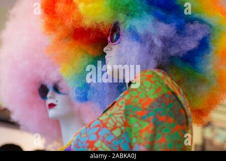 Deux mannequins blanc portant des lunettes de soleil avec de très gros curly perruques colorées sur leur tête, l'un rose et l'autre style arc-en-ciel Banque D'Images