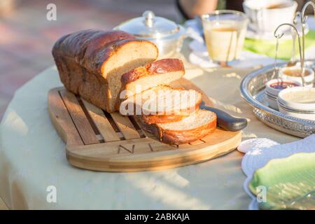 Petit-déjeuner fait maison brioche française sur une planche à découper, des confitures dans cups sur une journée ensoleillée en été le matin. Bon sentiment. Détail vert Banque D'Images