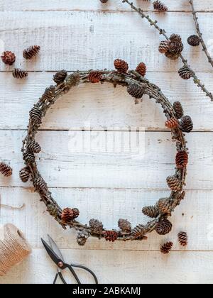 Couronne de Noël fabriqués à partir de matériaux naturels. Couronne de chêne fait main avec les cônes sur une table en bois blanc Banque D'Images