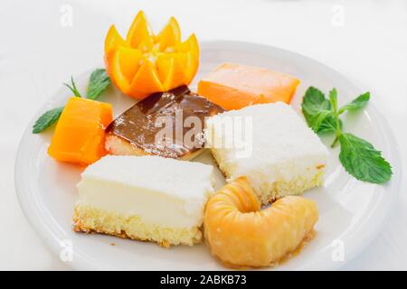 Décorées avec des douceurs orientales orange sur une plaque blanche sur fond blanc. Image horizontale Banque D'Images