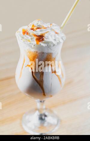 Lait frappé de macro avec crème fouettée et garniture au caramel en verre avec de l'éco-friendly de paille de bambou sur fond de bois. Concept de plastique Banque D'Images