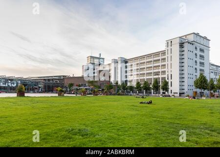 Eindhoven (Pays-Bas), le 1 juin 2019. L'klokgebouw et personnes portant sur la pelouse à côté de l'Ketelhuiplein sur Strijp S pendant le coucher du soleil. Banque D'Images