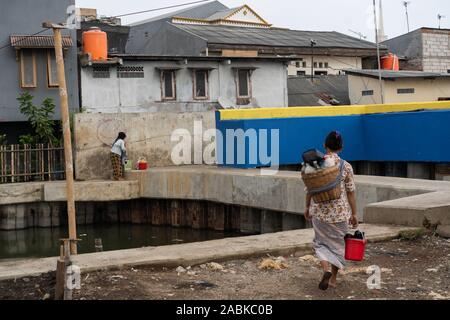 Au nord de Jakarta, Indonésie. 18 Oct, 2019. Les gens marchent dans le Kampung Aquarium, au nord de Jakarta, Indonésie, près d'un mur de protection. (Dpa : 'la mer, le mur et le pouvoir de détruire la nature") Credit : Fauzan Ijazah/dpa/Alamy Live News Banque D'Images