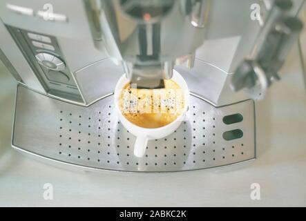 Machine à café filtre automatique dispense une délicieuse tasse de café parfumé chaud dans une tasse en céramique blanche. Café couleur saturée et magic aroma res Banque D'Images