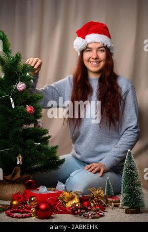 Happy woman in santa hat décore le Nouvel An des arbres dans l'après-midi Banque D'Images