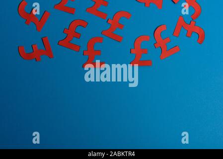 Jaune papier symboles de British pound monnaie sur fond bleu. Vue du dessus avec copie espace Banque D'Images