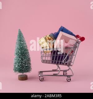 Concept d'achats de Noël, panier chariot avec arbre de Noël et boîte-cadeau sur Rose Banque D'Images