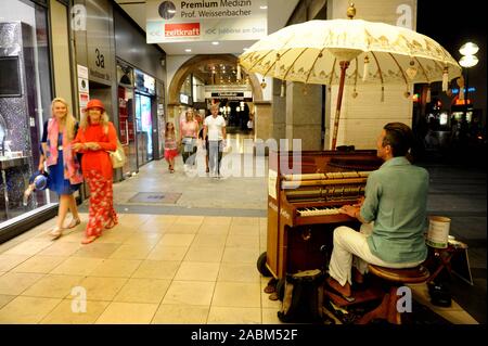 Un musicien de rue joue sur une chaude nuit d'été dans la zone piétonne de Kaufingerstraße. [Traduction automatique] Banque D'Images