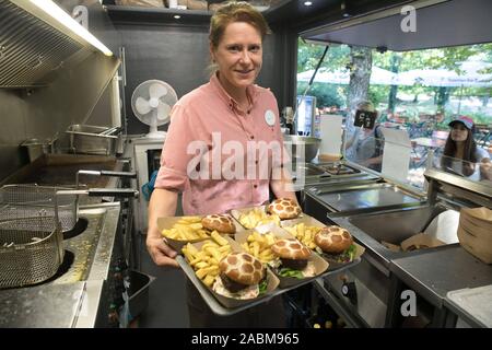 Chef d'équipe dans le service Nadine Eichhorst avec les hamburgers et les frites dans un camion alimentaire dans le zoo [traduction automatique] Banque D'Images