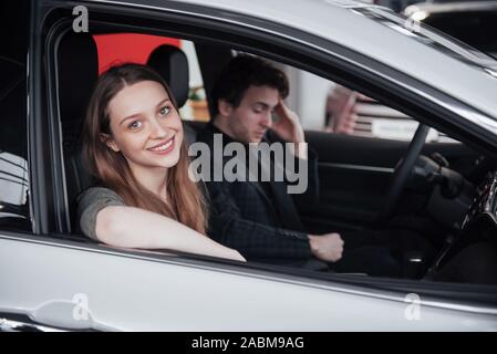 Fiers propriétaires. Beau young happy couple hugging debout près de leur voiture nouvellement acheté souriant joyeusement montrant des clés de voiture à l'appareil photo copyspace Banque D'Images