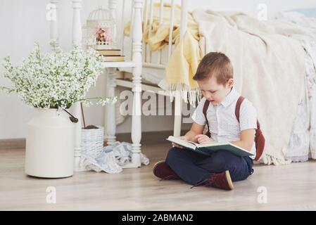 Adorable petit garçon va à l'école pour la première fois. Enfant avec sac et livre. Kid fait un porte-documents, chambre enfant sur un arrière-plan Banque D'Images