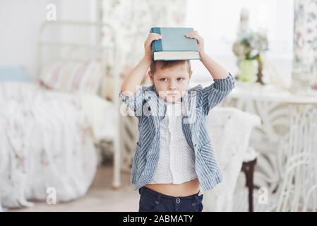 L'éducation, l'enfance, les gens, les devoirs et l'école concept - bored boy étudiant ou un manuel à la maison Banque D'Images