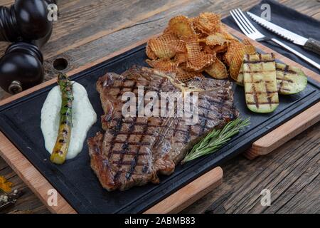 T-bone steak grillé assaisonné de fines herbes et servi avec de la marinade une planche à découper dans un steakhouse. De délicieux plats au restaurant Banque D'Images