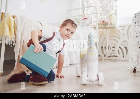 Adorable petit garçon va à l'école pour la première fois. Enfant avec sac et livre. Kid fait un porte-documents, chambre enfant sur un arrière-plan Banque D'Images