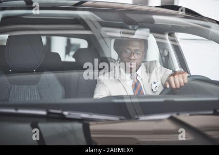 Vue avant du beau élégant africain des affaires sérieuses homme conduit une voiture Banque D'Images
