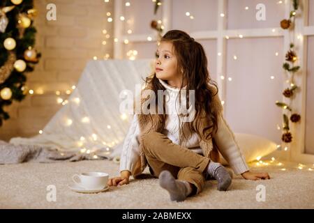 Jolie petite fille enfant Boissons Chocolat chaud à partir de la grande tasse à la maison. Noël Banque D'Images