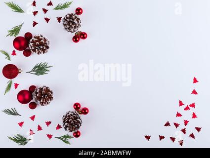 Noël et Nouvel An la composition. Cadre fait de noël rouge silhouette de sapin, des branches de pins, cône sur fond blanc. Mise à plat, vue du dessus Banque D'Images