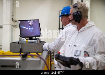 Brunsbüttel (Allemagne). 28 novembre 2019, le Schleswig-Holstein, Brunsbüttel : Deux techniciens démantèlement observer sur un écran la tête de coupe du robot sous-marin Azuro avec technologie de coupe à l'eau pendant une manifestation s'exécuter sur une machine à vapeur sèche cheveux dans la salle de l'inondation dans le bâtiment réacteur de la centrale nucléaire de Brunsbüttel (KKB). Avec le démantèlement de l'intérieur de la cuve du réacteur, le démantèlement de la centrale nucléaire de l'Elbe, qui sera arrêté en 2011, a commencé. Photo : Christian Charisius/dpa dpa : Crédit photo alliance/Alamy Live News Banque D'Images