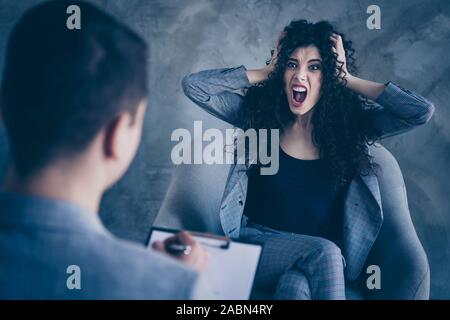 Portrait de sa belle elle fou attrayant émotionnelle fou furieux aux cheveux ondulés irritée girl sitting in chair pleurer crier hurler crier échec Banque D'Images