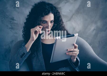 Close-up portrait de sa elle belle belle belle charme chic chic fille brune ondulée étonné sitting in chair la lecture des nouvelles e-livre numérique Banque D'Images