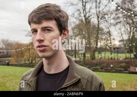 Close up tête et les épaules d'un jeune homme dans la fin de l'adolescence ou au début de la vingtaine de marcher dans un parc. Banque D'Images