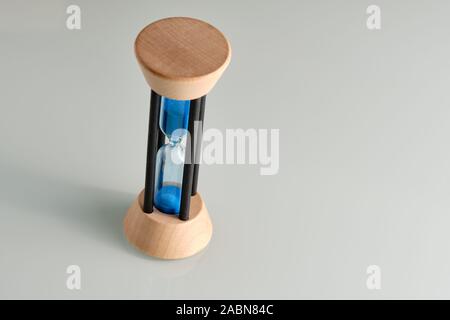 Sablier en bois et verre avec sable bleu qui traverse tout le temps passe Banque D'Images