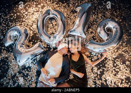 La célébration du Nouvel An. Un homme et une femme célébrer avec des ballons et de se coucher en confetti Banque D'Images