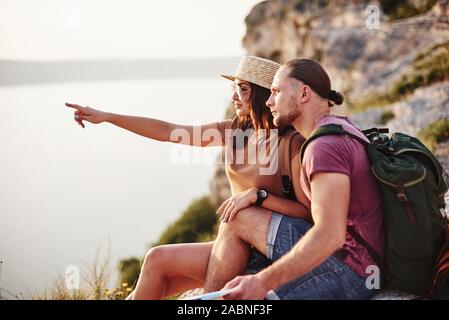 Jeune couple reposant de marcher au bord de la montagne. Se demande dans quelle mesure est-il de la côte d'autres Banque D'Images