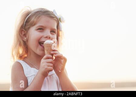 Cute smiling little girl eating ice cream au fond de lac et forêt Banque D'Images